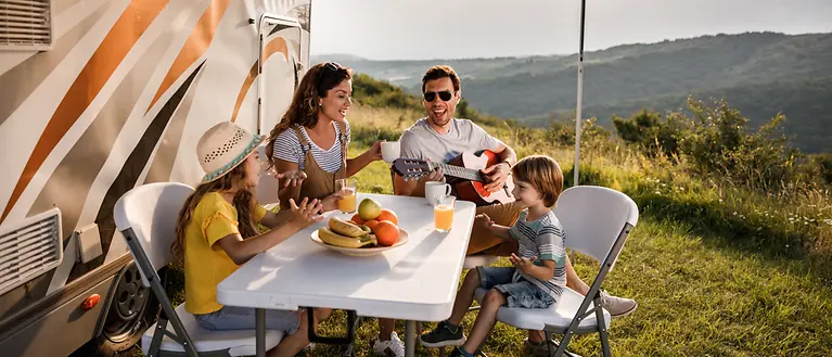 Mutter, Vater und ihre zwei Kinder sitzen an einem Campingtisch und singen. 