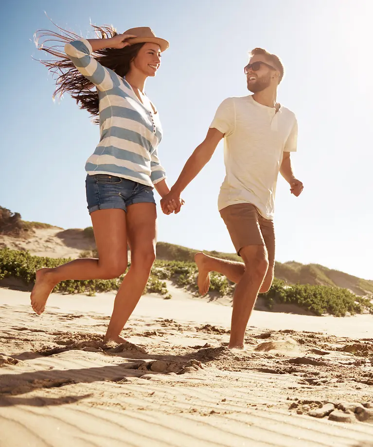 Vier Freunde laufen am Strand in Richtung Wasser