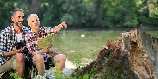 Eine Frau und ein Mann sitzen auf einer Wiese und beobachten etwas. 