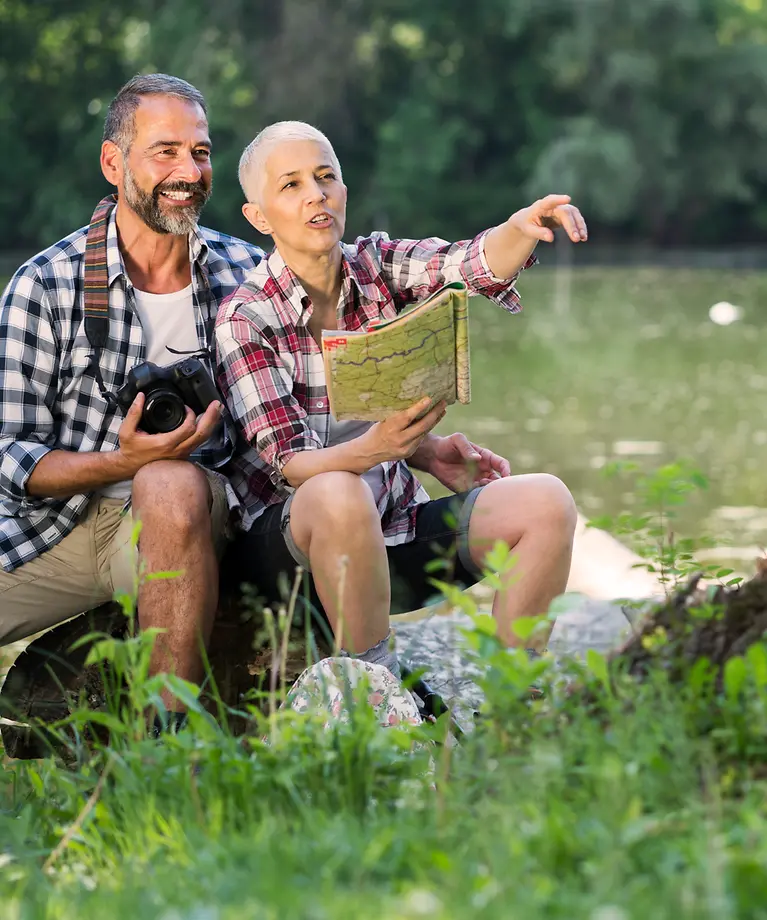 Eine Frau und ein Mann sitzen auf einer Wiese und beobachten etwas. 