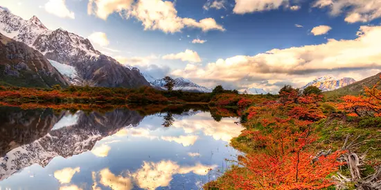 Man sieht eine farbenfrohe Landschaft mit Bergen und See.