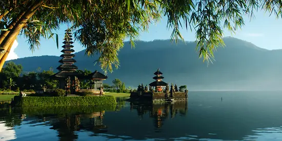 Man sieht einen Teil eines Palast, der am Wasser liegt und im Hintergrund sind Berge zu erkennen.