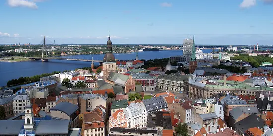 Zusehen ist eine Stadt, die an einem Fluss liegt und eine Brücke führt von einer Seite zur anderen.