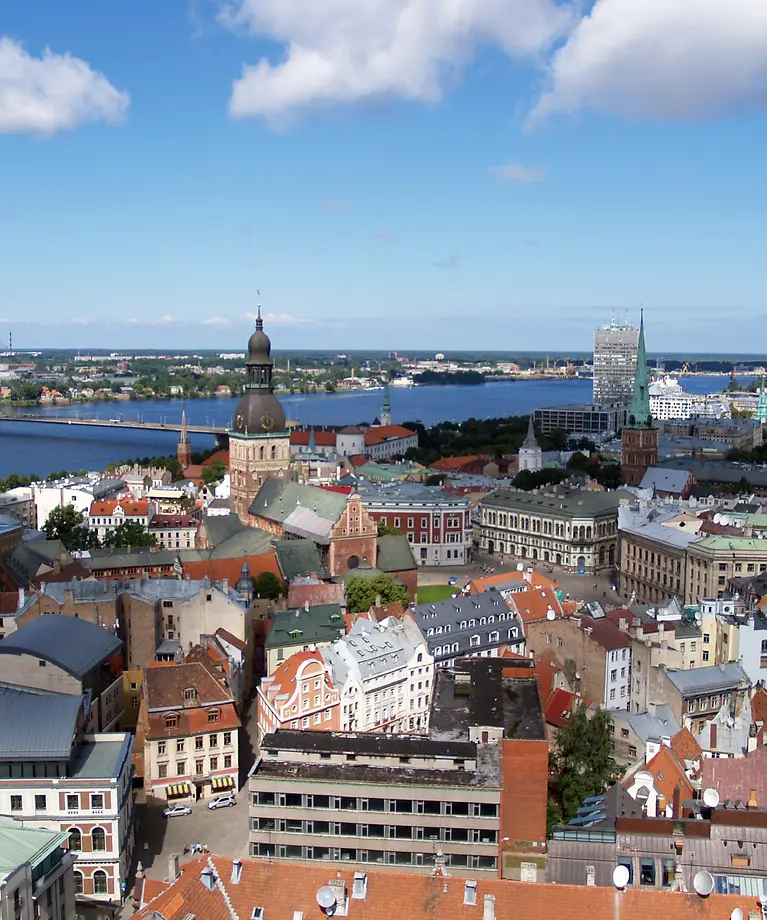 Zusehen ist eine Stadt, die an einem Fluss liegt und eine Brücke führt von einer Seite zur anderen.