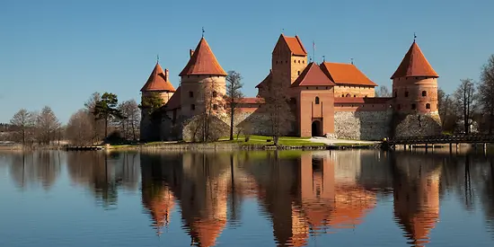 Man erkennt eine Burg aus Backstein, die sich auf einer Insel befindet. Im Hintergrund ist blauer Himmel.