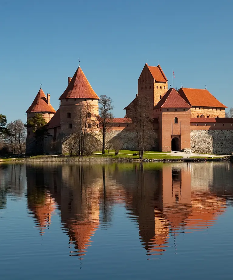 Man erkennt eine Burg aus Backstein, die sich auf einer Insel befindet. Im Hintergrund ist blauer Himmel.