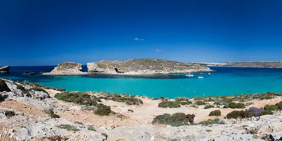 Man erkennt eine Bucht mit türkisem Wasser. Im Hintergrund ist eine kleine Insel zu sehen. 