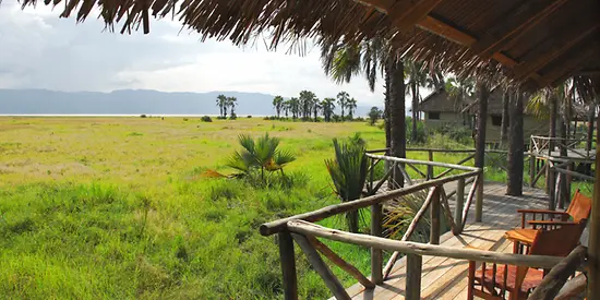 Man sieht eine überdachte Terrasse aus Holz. Die Terrasse befindet sich mitten auf einer grünen Wiese.