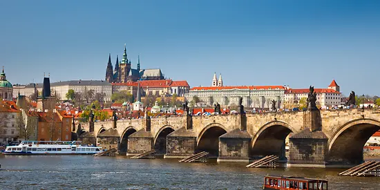 Man erkennt eine große gemauerte Brücke, die über einen Fluss ragt. Auf dem Fluss fahren Schiffe. Im Hintergrund sind Gebäude.