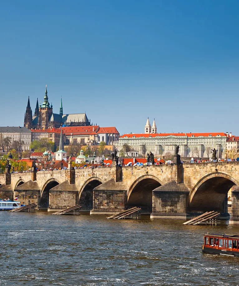 Man erkennt eine große gemauerte Brücke, die über einen Fluss ragt. Auf dem Fluss fahren Schiffe. Im Hintergrund sind Gebäude.