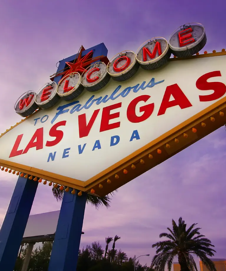 Man erkennt ein riesiges Schild auf dem "Welcome to fabulous Las Vegas Nevada" steht. 