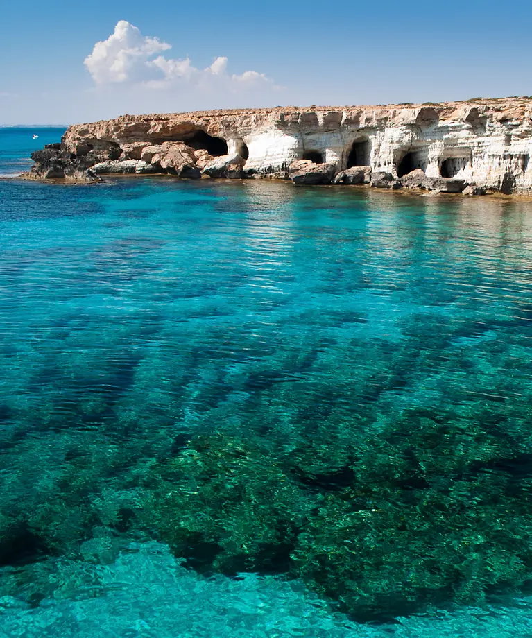 Man erkennt eine Bucht mit kristallklarem türkisen Wasser. 