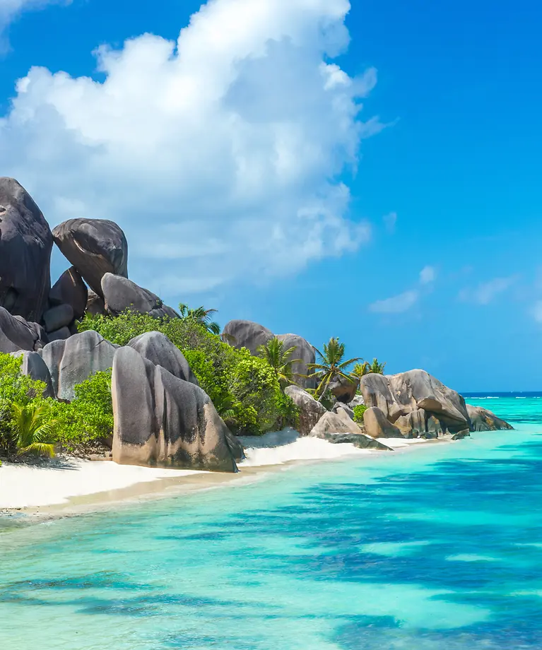 Man sieht einen Sandstrand mit Granitfelsen.