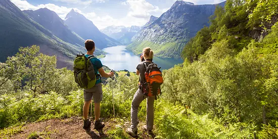 Ein Paar steht mit Wanderrucksäcken vor einem Bergpanorama.