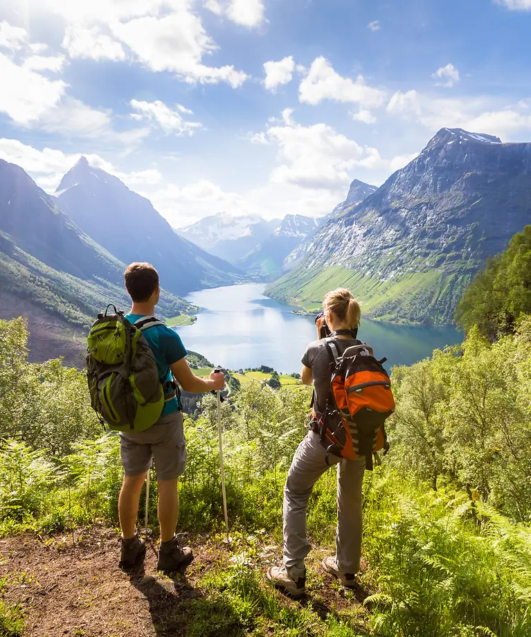 Ein Paar steht mit Wanderrucksäcken vor einem Bergpanorama.