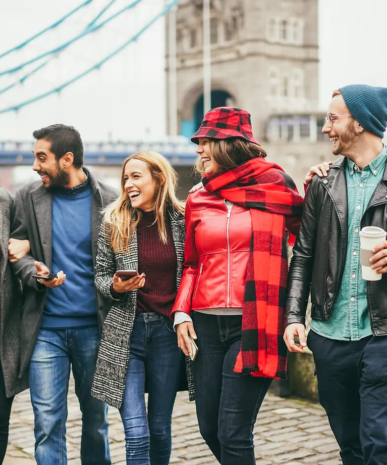 Fünf Personen stehen vor der London Bridge und lachen.