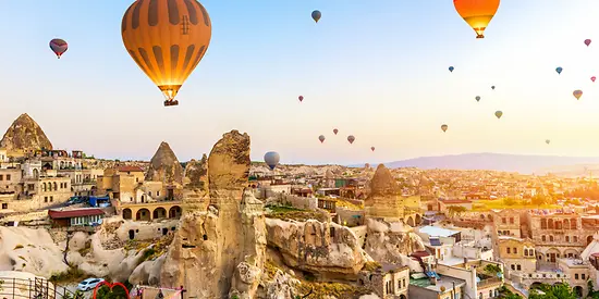 Zu erkennen sind viele Heißluftballons und Felsen.