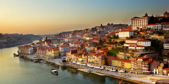 Man sieht einen Hügel mit der Altstadt von Porto. Im Vordergrund ist ein Fluss zu sehen.