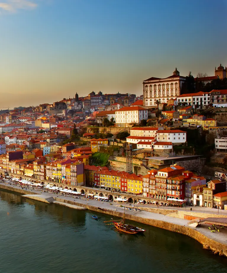 Man sieht einen Hügel mit der Altstadt von Porto. Im Vordergrund ist ein Fluss zu sehen.