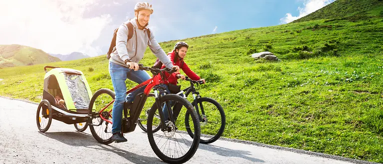 Ein Mann und eine Frau sitzen auf einem E-Bike und machen eine Tour in den Bergen. 