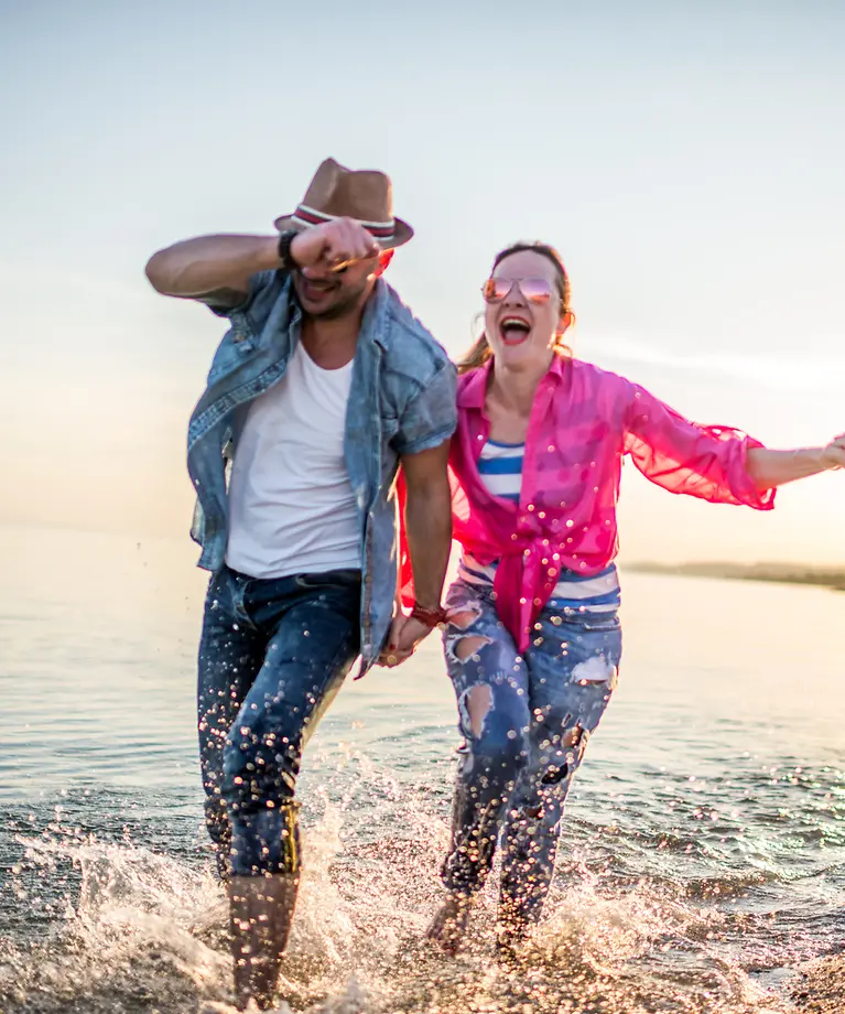 Drei Freunde gehen am Wasser spazieren und tragen alle eine Sonnenbrille.